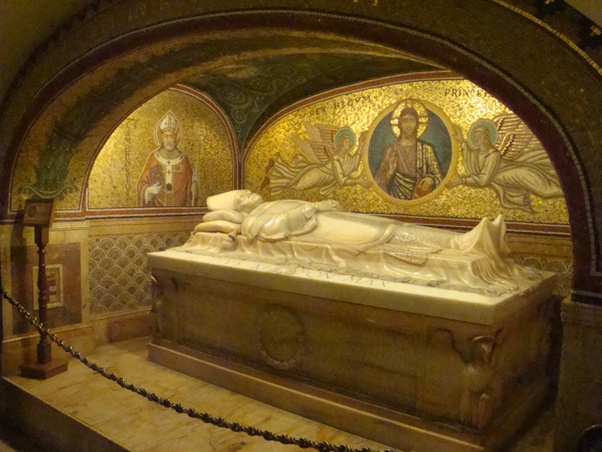 A stone sarcophagus inside a church crypt with gold mosaics