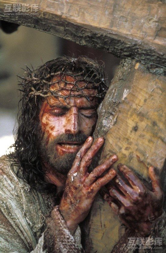 A scene from The Passion of the Christ showing Jesus carrying a wooden cross beam