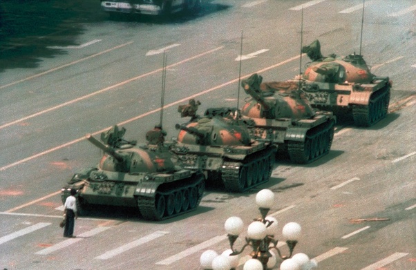 Tank Man standing in front of a line of tanks at Tiananmen Square